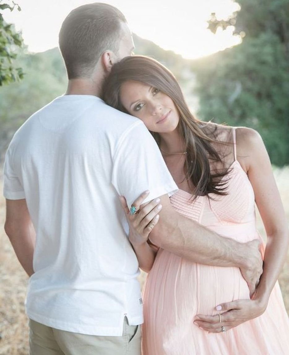 Family kissing mom's baby bump in maternity photo session