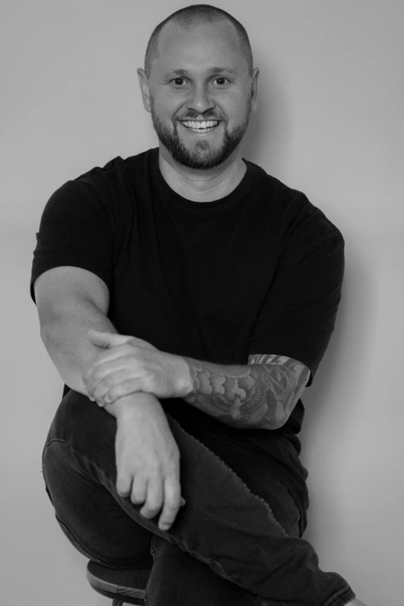 a man sitting on a stool smiling