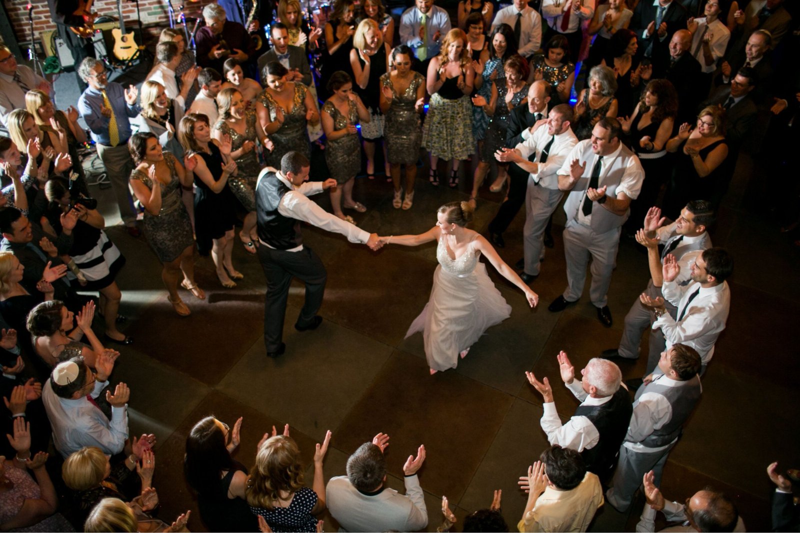 Couple's first dance with wedding party watching and celebrating joyfully.