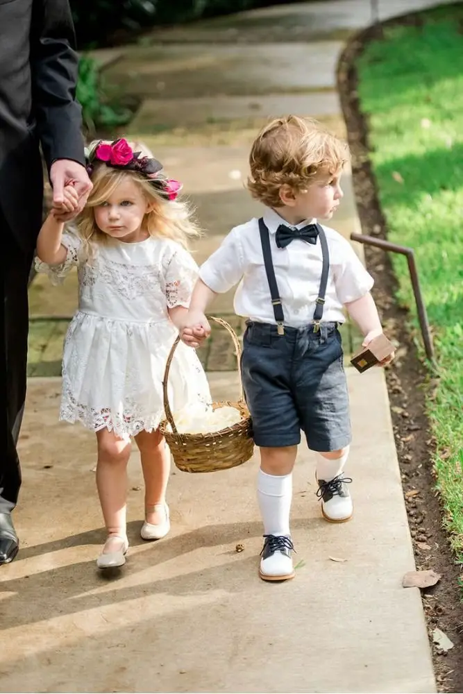 Flower girl and ring bearer smiling in their wedding party outfits.