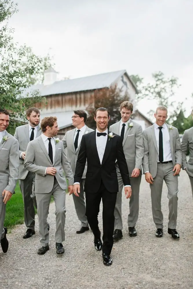 Groom standing with his groomsmen, all dressed up for the wedding party celebration.