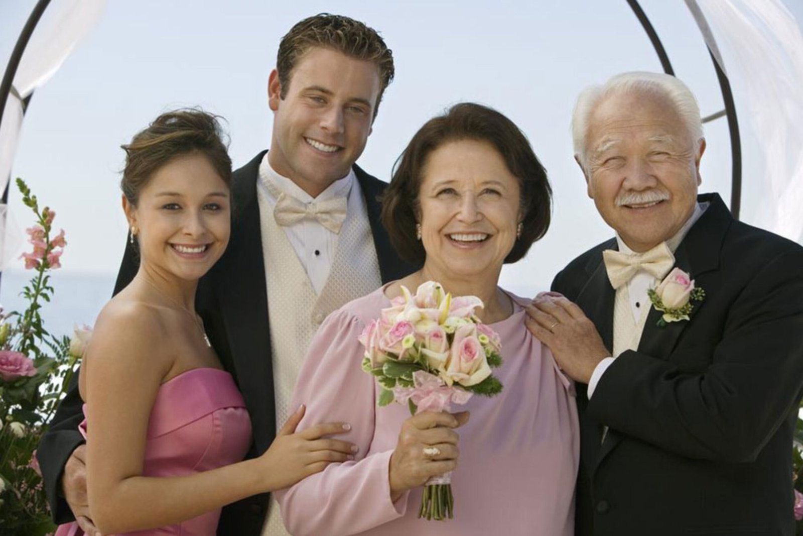 Groom with his parents at the wedding party, smiling and celebrating together.