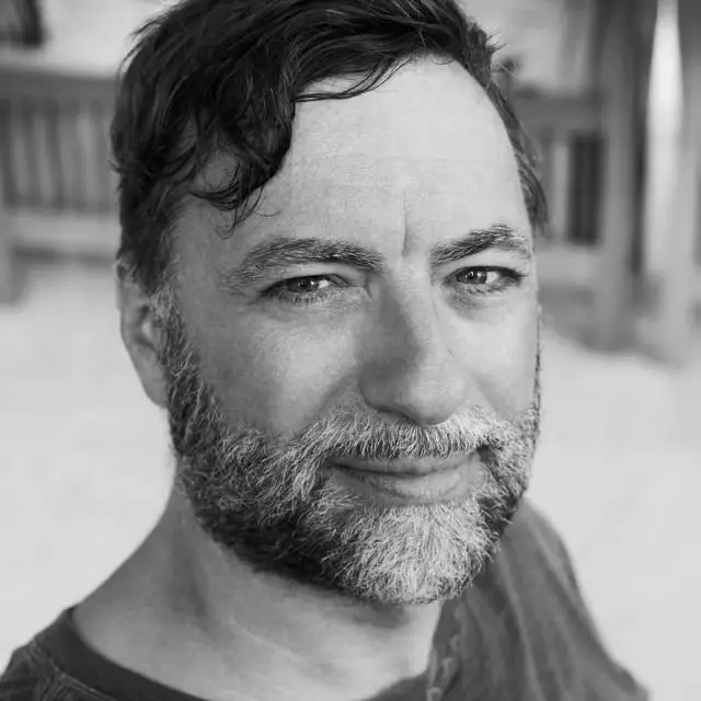 A black and white photo featuring a bearded man, capturing his thoughtful expression and rugged charm.