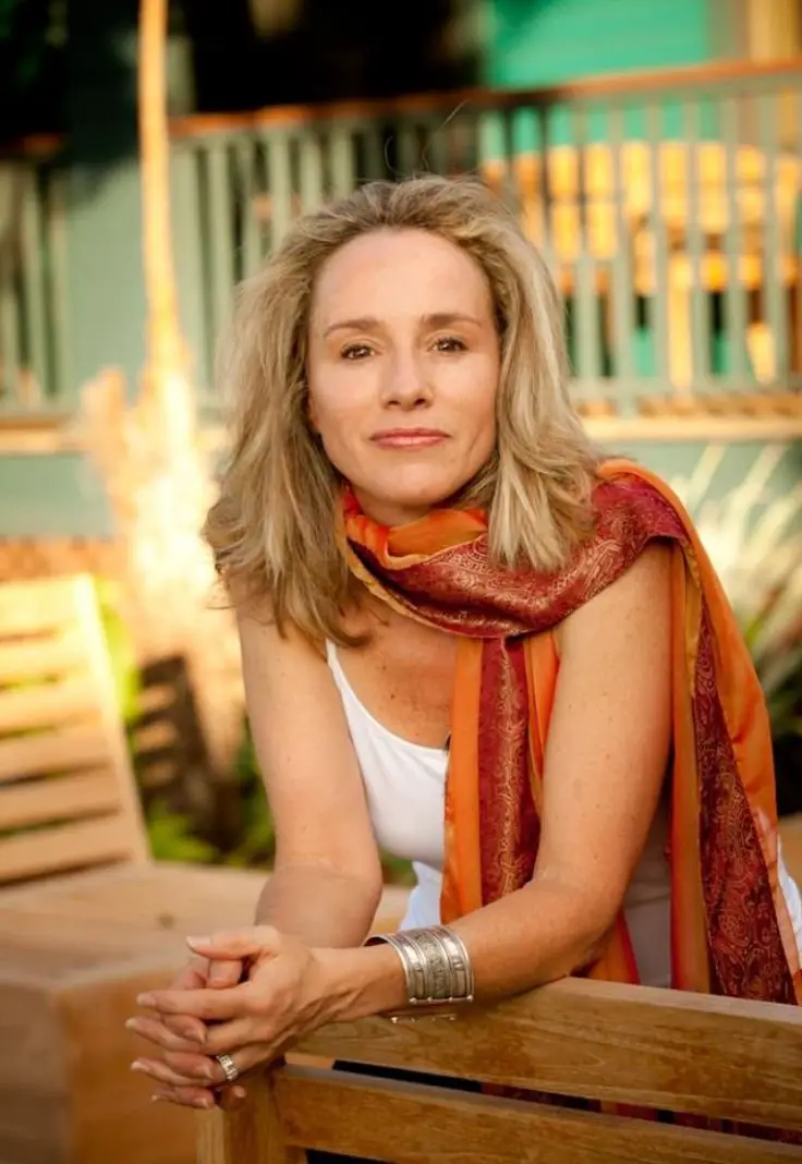 A woman wearing an orange scarf sits on a bench, enjoying a moment of relaxation outdoors.