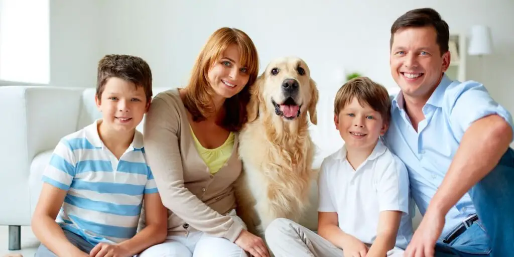 A family and their dog are seated on the floor, sharing a loving moment during a fun photoshoot.