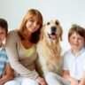 A family and their dog are seated on the floor, sharing a loving moment during a fun photoshoot.