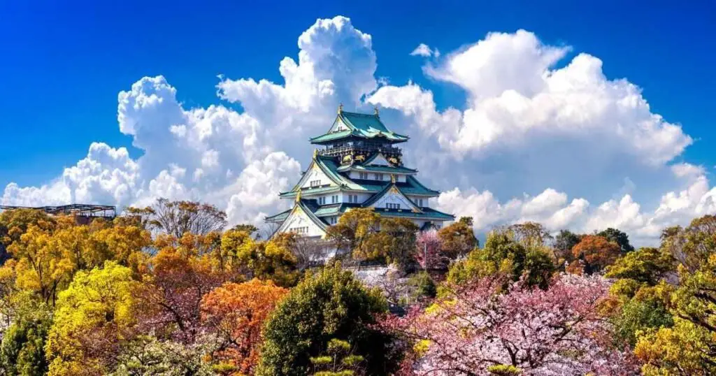 A majestic castle nestled among lush trees, with fluffy clouds drifting overhead, creating a serene landscape.