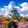 A majestic castle nestled among lush trees, with fluffy clouds drifting overhead, creating a serene landscape.