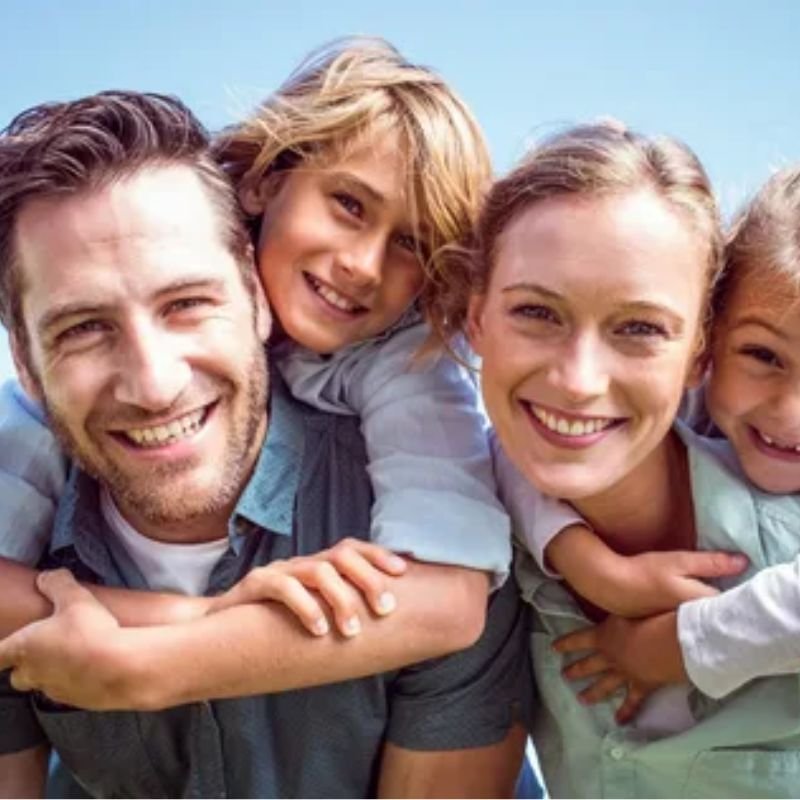 A family portrait featuring two children and one adult, capturing a moment of joy and togetherness in a natural setting.