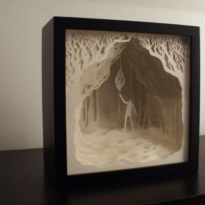 A paper cut silhouette of a man standing amidst trees in a forest, showcasing creative photography techniques.