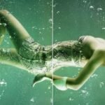 A woman in a green dress gracefully floats in the water, embodying the essence of mermaid photography.