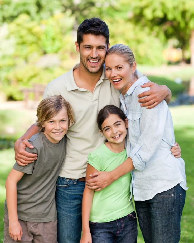  A family smiles together for a photo in a sunny park, capturing a joyful moment in their outdoor gathering.