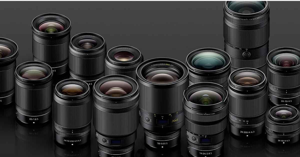 A collection of various camera lenses in different sizes arranged on a reflective black surface.