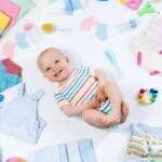 A baby nestled among colorful photography props and various baby items, creating a cozy and playful scene.