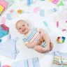 A baby nestled among colorful photography props and various baby items, creating a cozy and playful scene.