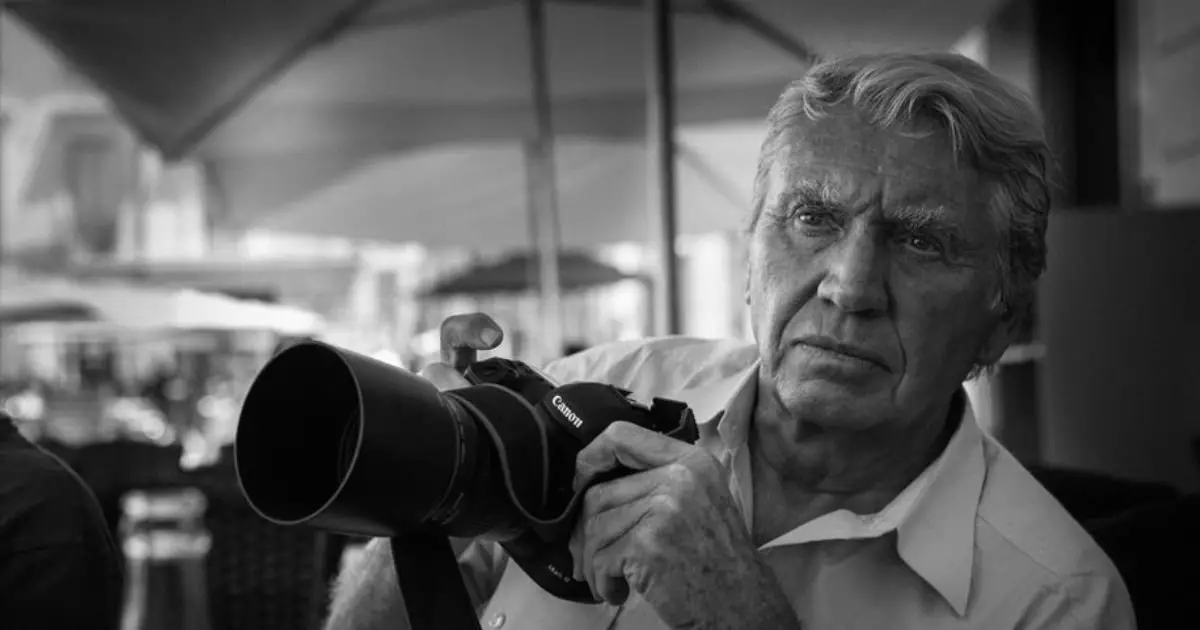 An experienced war photographer, an older man, focuses on the camera, symbolizing his dedication to capturing powerful images.