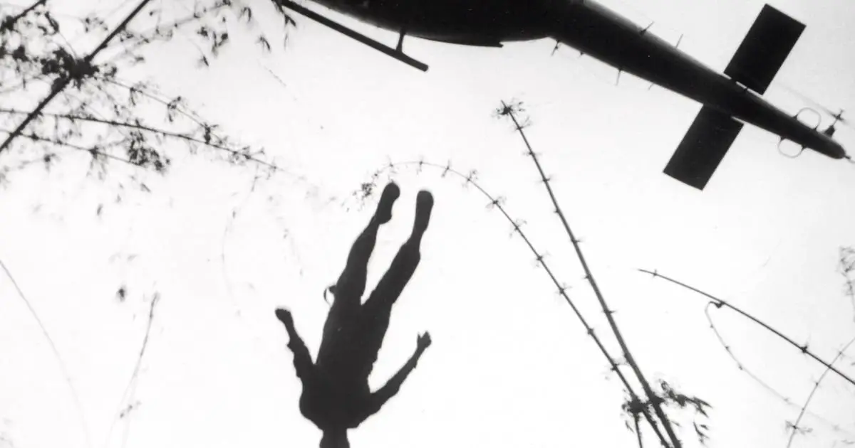 A man is seen falling from a helicopter, highlighting the intense and dangerous situations faced by famous war photographers.