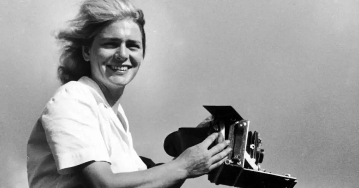  A woman, known for her impactful war photography, beams as she holds her camera, ready to document the world around her.